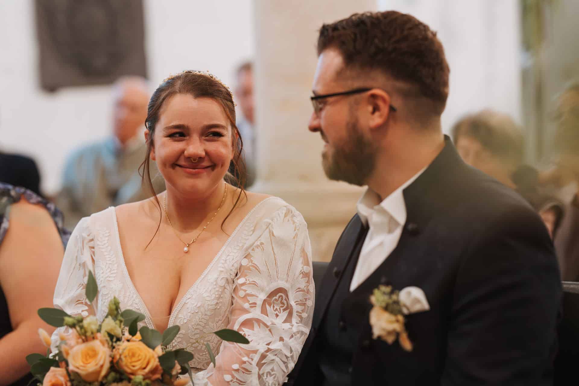 Braut und Bräutigam lächeln sich während der Trauung in der Kirche an